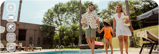 Família de três pessoas caminha à beira da piscina em um resort ensolarado, segurando chapéus, com palmeiras e espreguiçadeiras ao fundo.